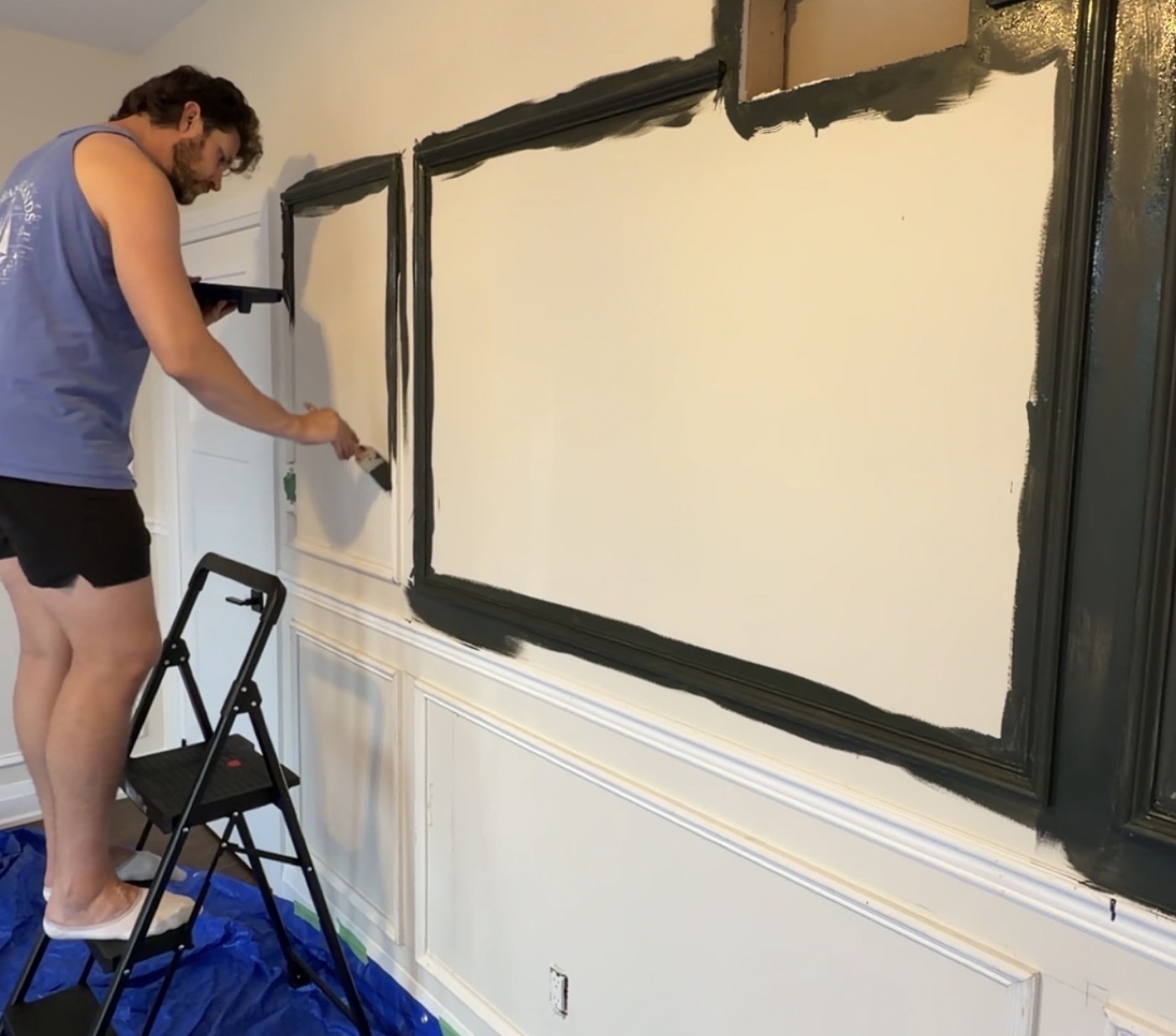 Justyn on a step stool painting the panelling in his office dark green