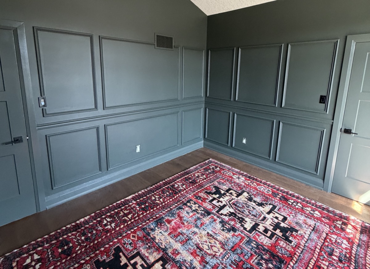 The office repainted dark green with new panelling and a red rug